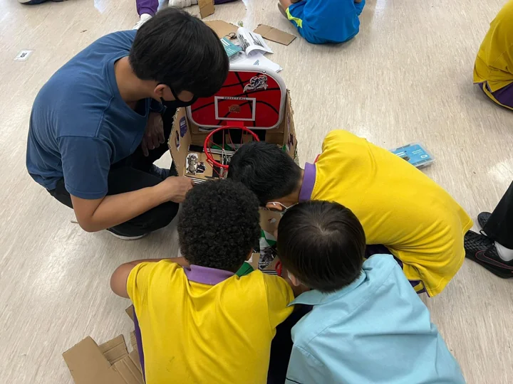 A coach helping students assemble a hands-on project
