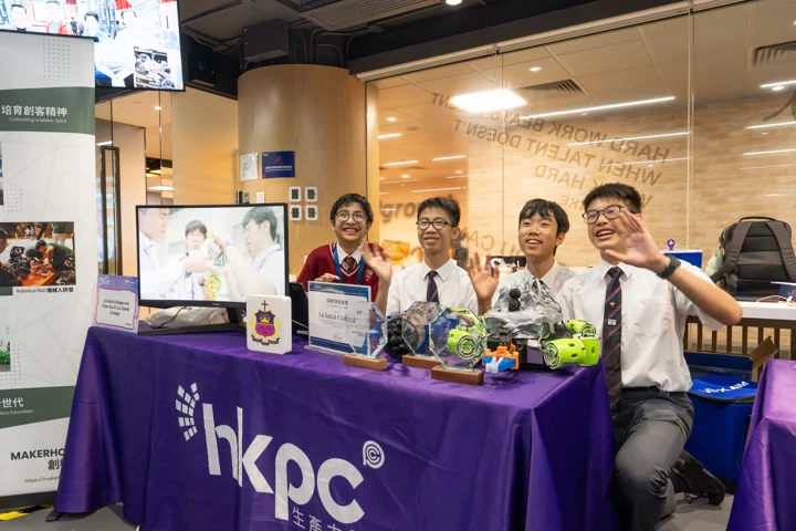 Four smiling students showcasing their underwater robot and awards at a MakerHolic exhibit