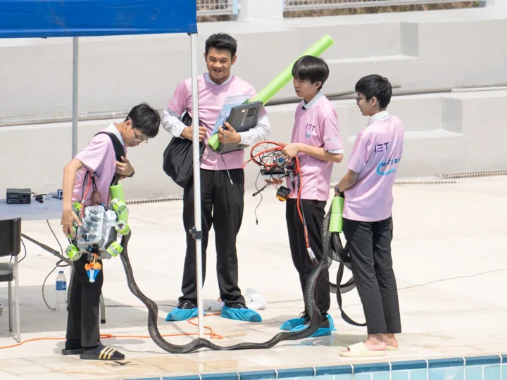 Students testing an underwater robot together at a pool